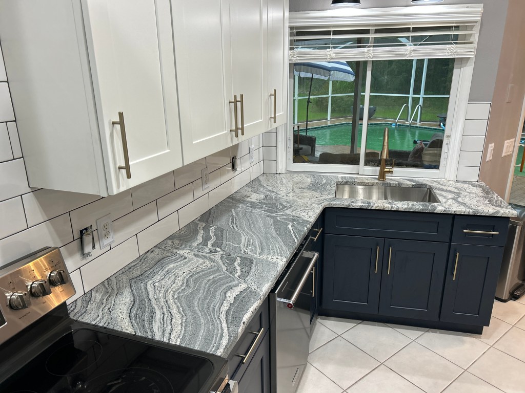 Two-tone kitchen with white and navy shaker cabinets, granite countertops and subway tile in Homosassa, Florida